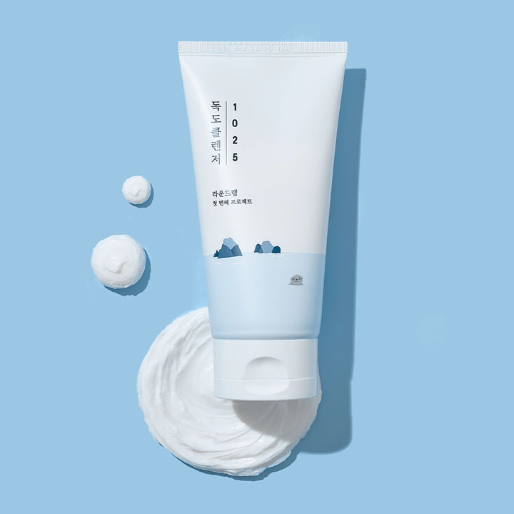 ROUND LAB Korean Beauty Dokdo facial wash on a blue background, showcasing the rich and white cleanser texture